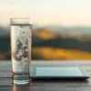 A glass of crystal-clear hydrogen-infused water stands in the foreground, its gentle bubbles reflecting the warm, soft lighting. In the midground, a tablet with a gastric acid molecule model hovers, symbolizing the potential effects of hydrogen water on acid reflux. The background features a soothing, blurred landscape of rolling hills, evoking a sense of natural balance and wellness. The overall scene conveys a thoughtful, investigative mood, inviting the viewer to consider the relationship between hydrogen water and gastrointestinal health.