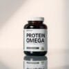 A sleek and modern protein supplement bottle, showcasing the "Protein Omega" label in a clean, minimalist design. The bottle is positioned on a reflective, glass-like surface, casting a subtle shadow below. Soft, directional lighting illuminates the supplement from the side, creating a sense of depth and dimension. The overall scene has a professional, high-quality aesthetic, inviting the viewer to imagine the premium quality of the product. The background is a simple, neutral color that allows the supplement bottle to be the focal point, drawing the eye to the key details and branding.